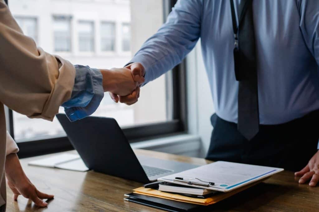 An insurance agent is shaking hands with their client.