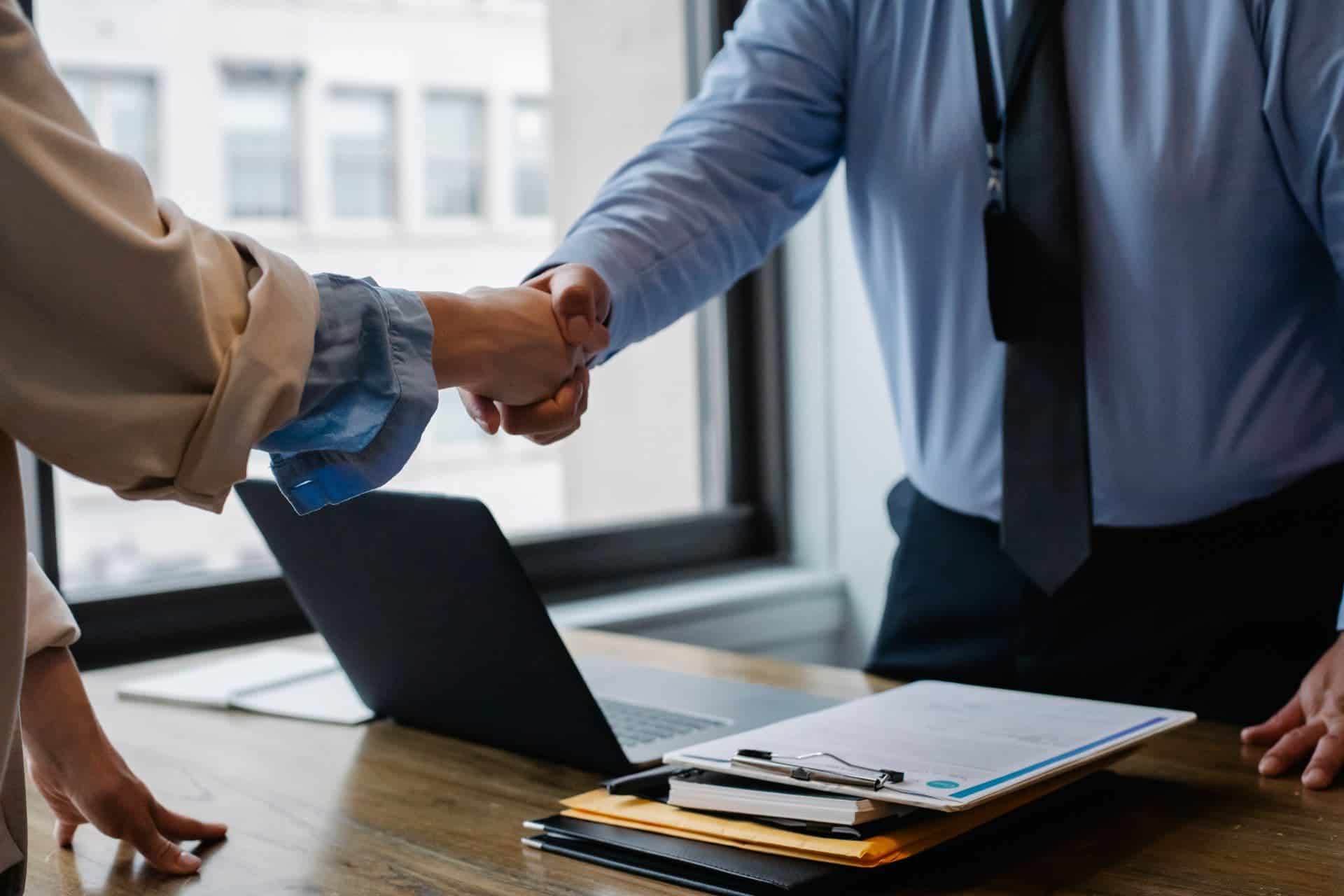 An insurance agent is shaking hands with their client.